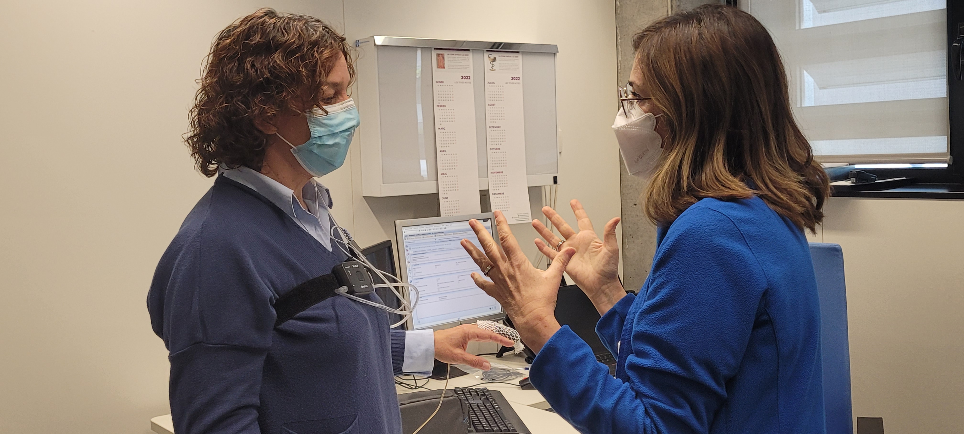 Una infermera explicant a una pacient com col·locar-se un polígraf de son.
