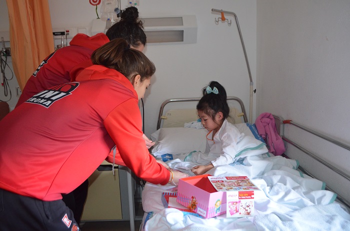 Jugadores de l'equip de bàsquet femení UNI Girona Spar Citylift visitant una nen ingressada a Pediatria