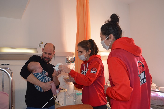Jugadores de l'equip de bàsquet femení UNI Girona Spar Citylift visitant un nen ingressat a Pediatria