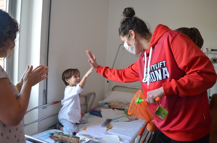 Jugadores de l'equip de bàsquet femení UNI Girona Spar Citylift visitant un nen ingressat a Pediatria