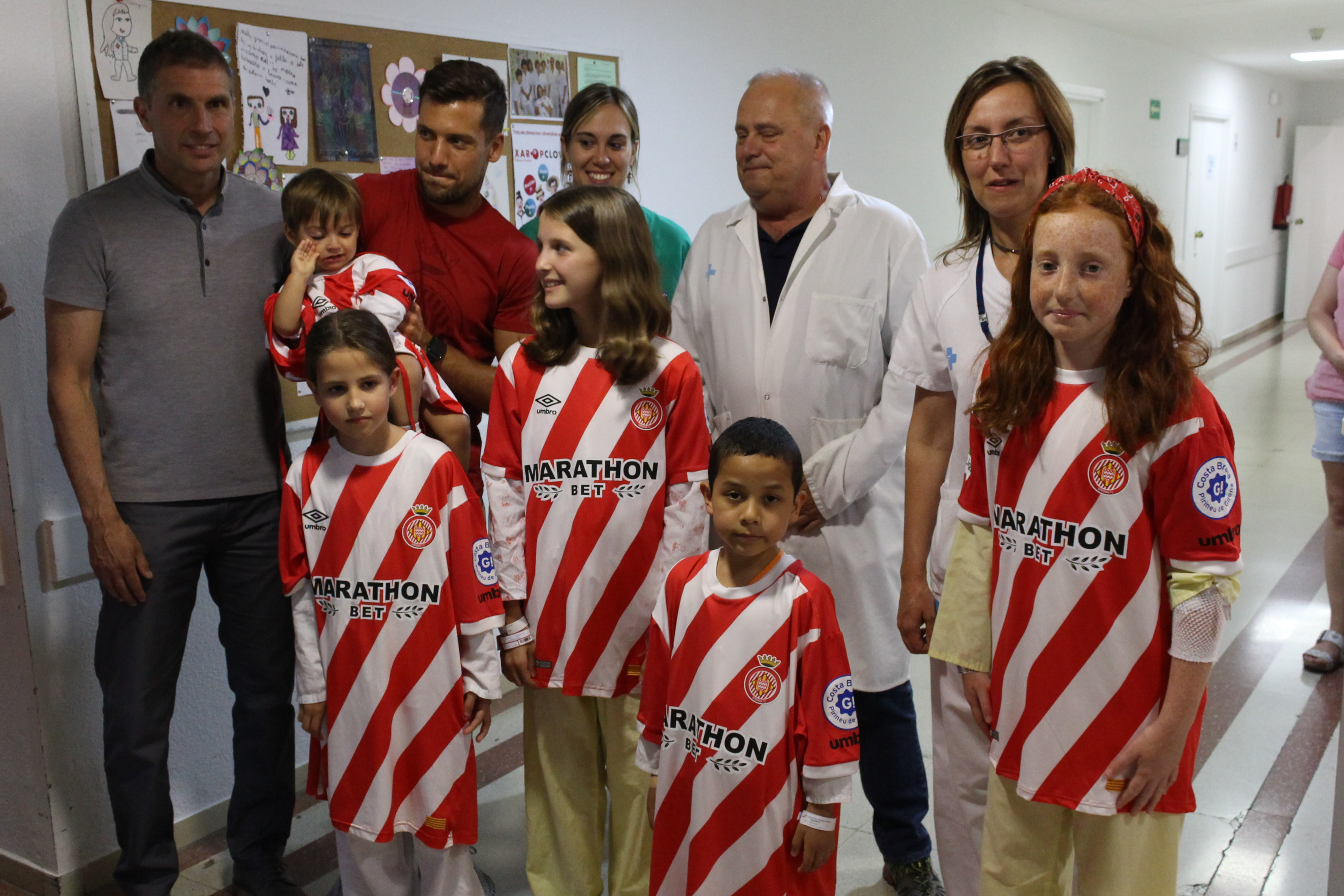 jugadors del Girona i professionals del Trueta amb els nens ingressatant la samarreta del Girona convertida en bata