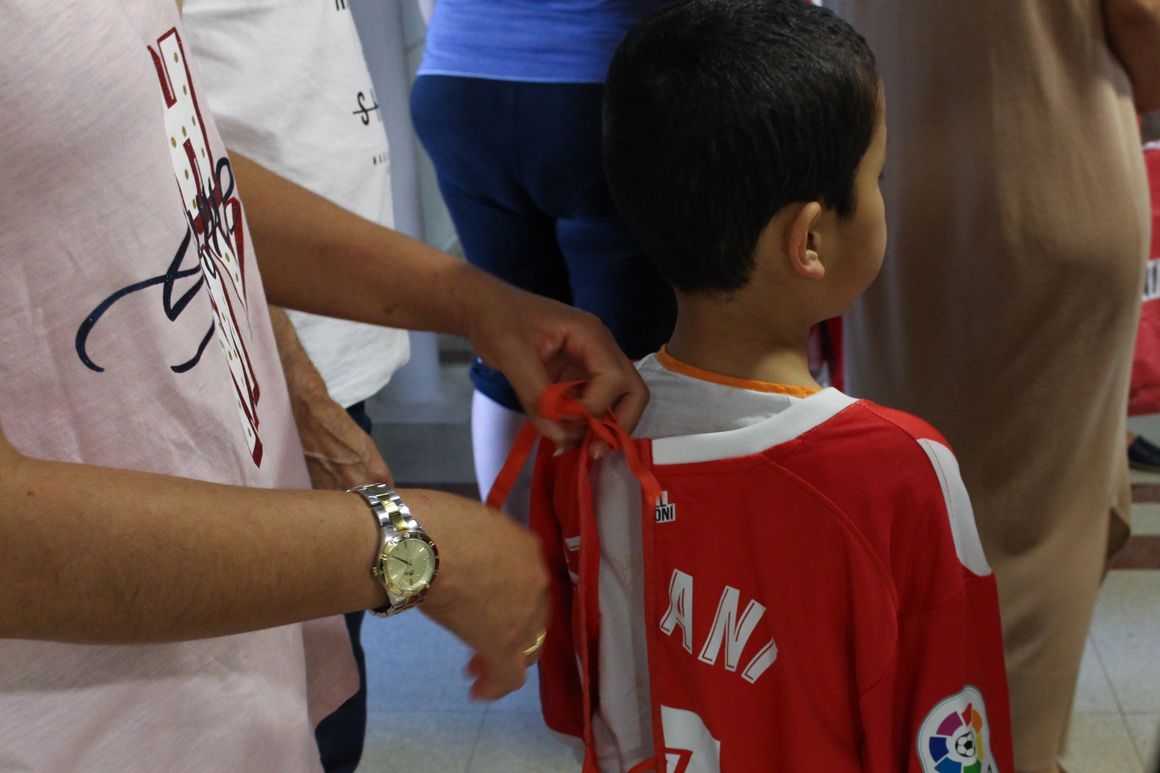 un jugador del Girona lliga a un nen la samarreta del Girona de fútbol reconvertida en bata d'hospital