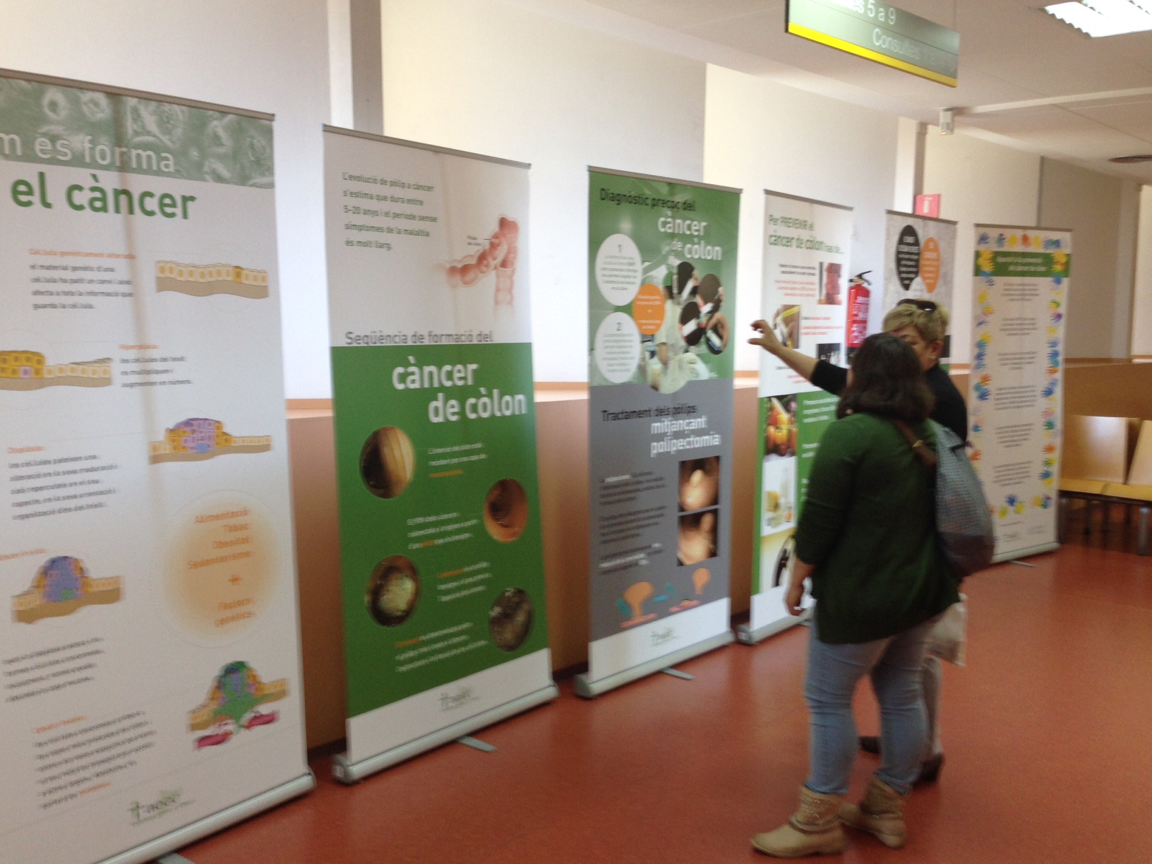 Uns usuaris miren l'exposició sobre el Programa de Cribratge de Càncer de Còlon i Recte al CAP Figueres
