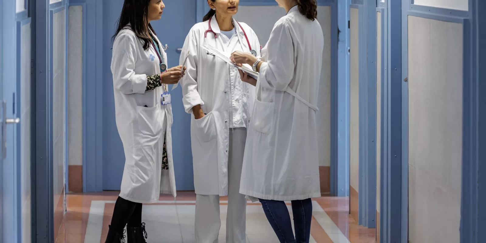 Tres profesionales sanitarias conversando en un pasillo del centro médico