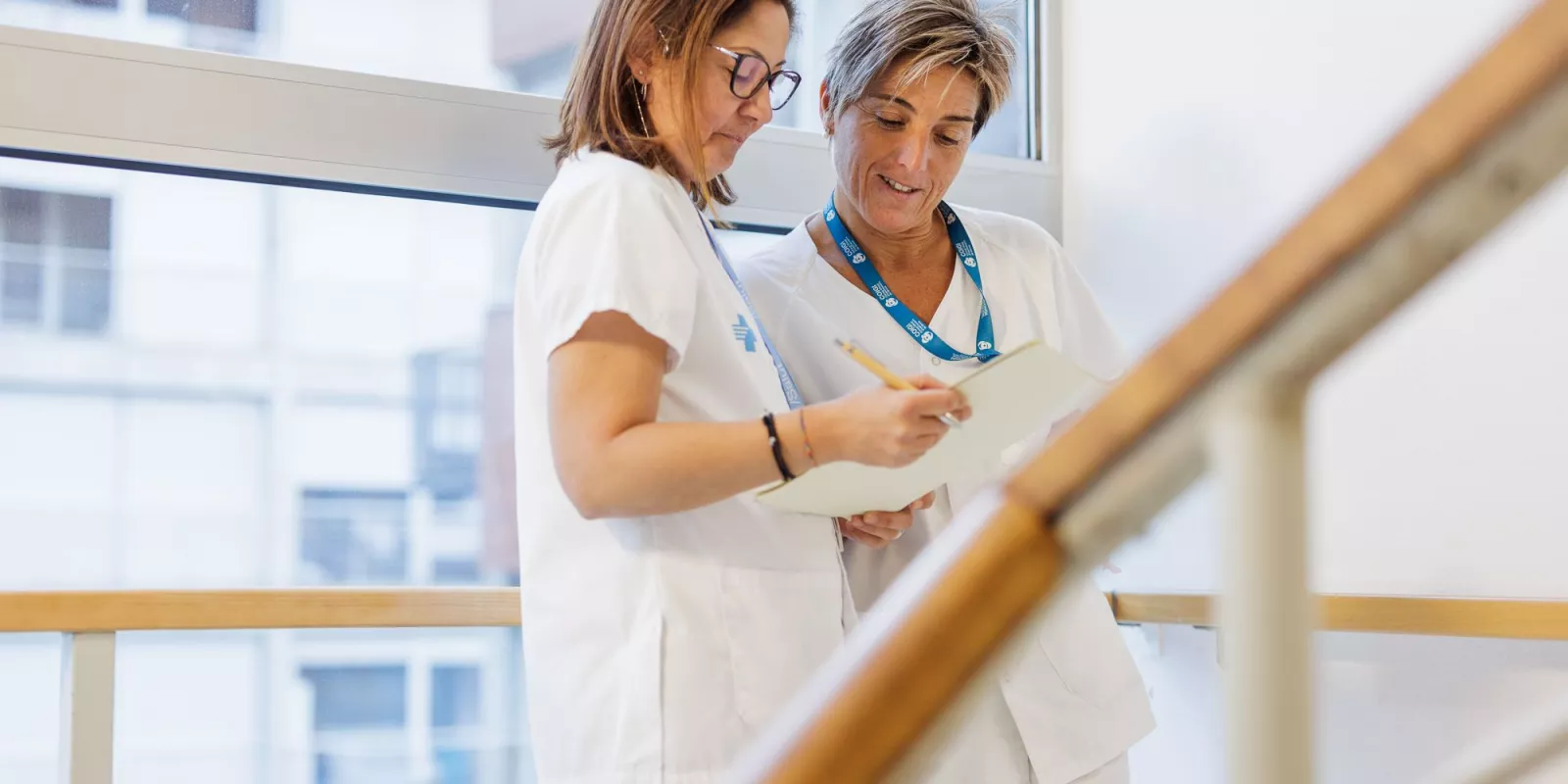 Dues professionals de la salut revisant un document a l'escala d'un edifici