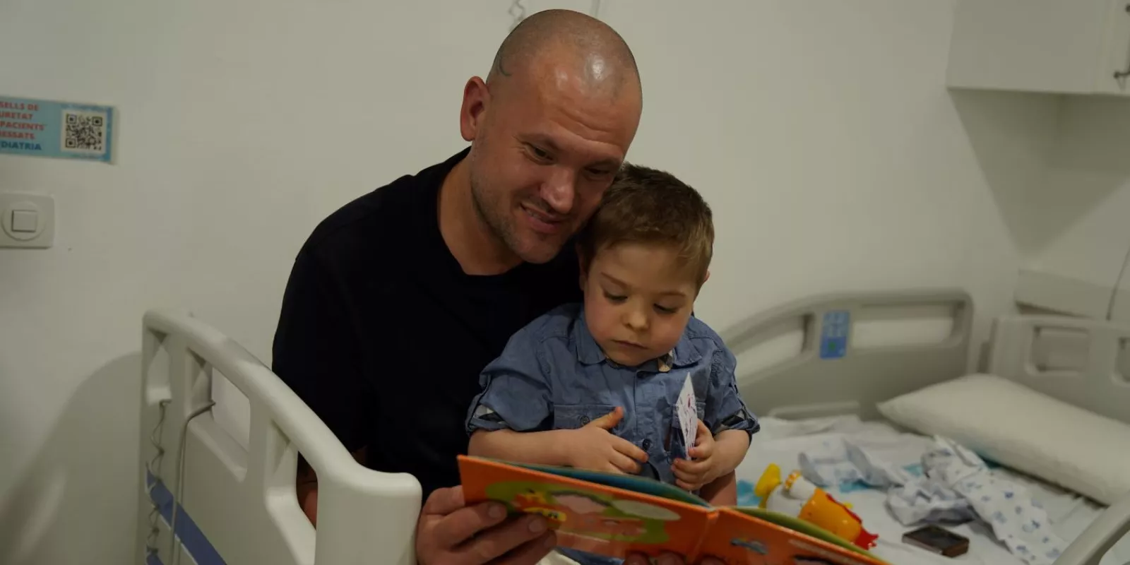 Un pacient pediàtric i un familiar fullegen un llibre en el marc de la celebració de Sant Jordi 2026 al Trueta.