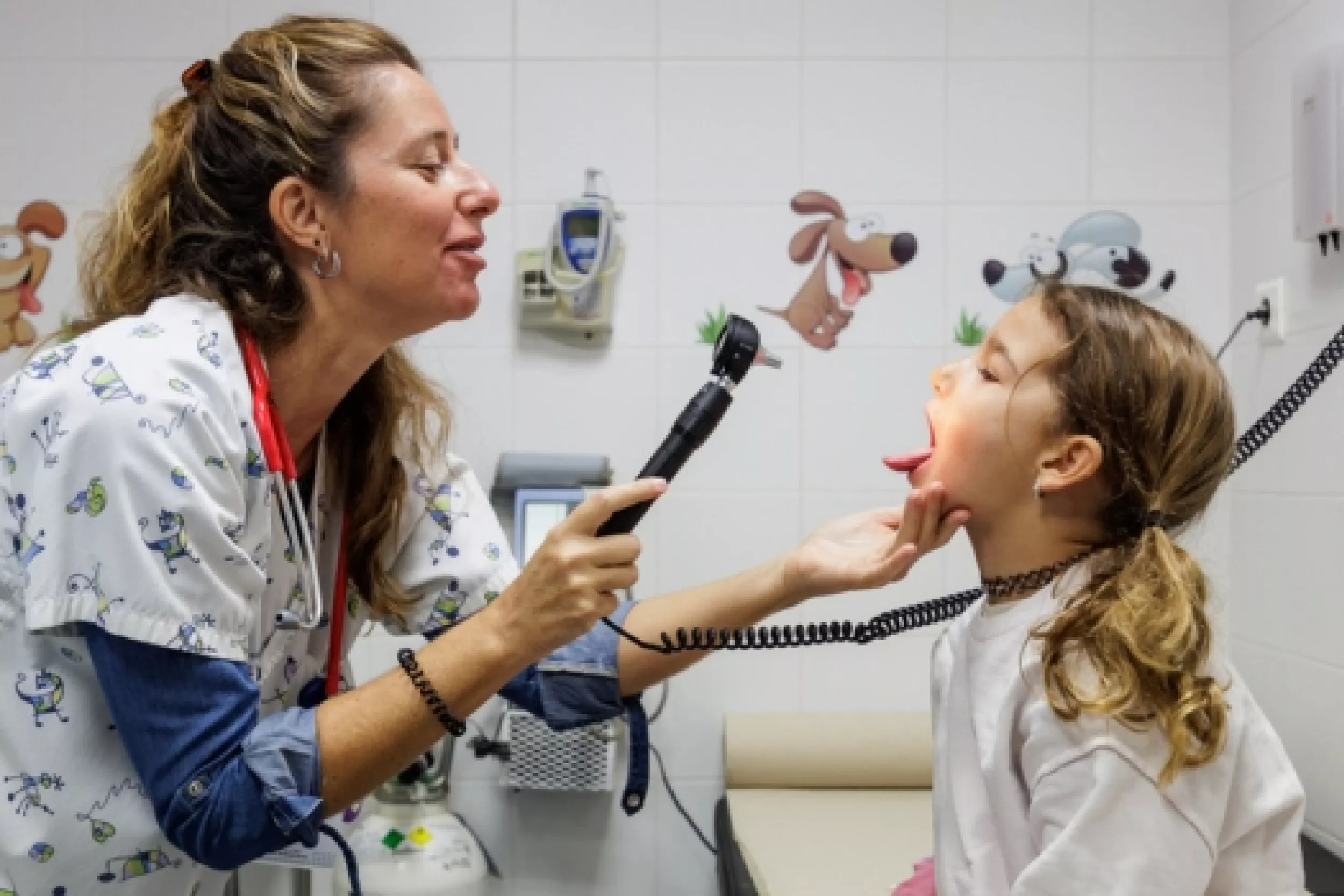 Una pediatra revisando la garganta de una niña