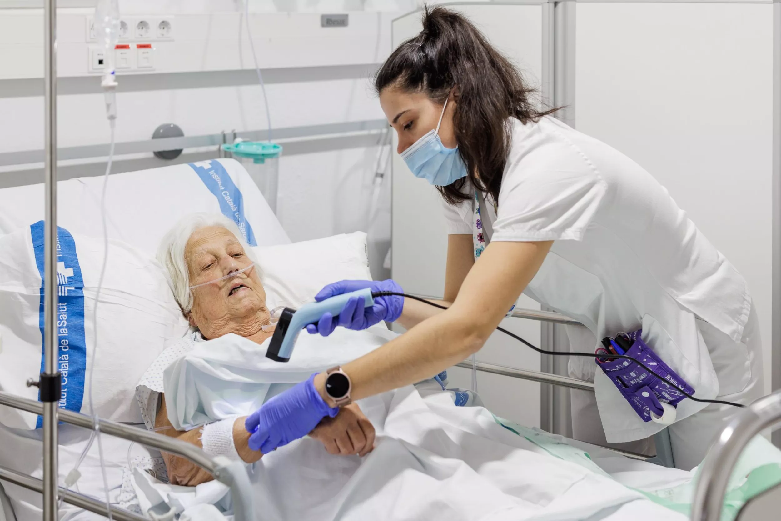 Infermera revisant una pacient que està estirada al llit