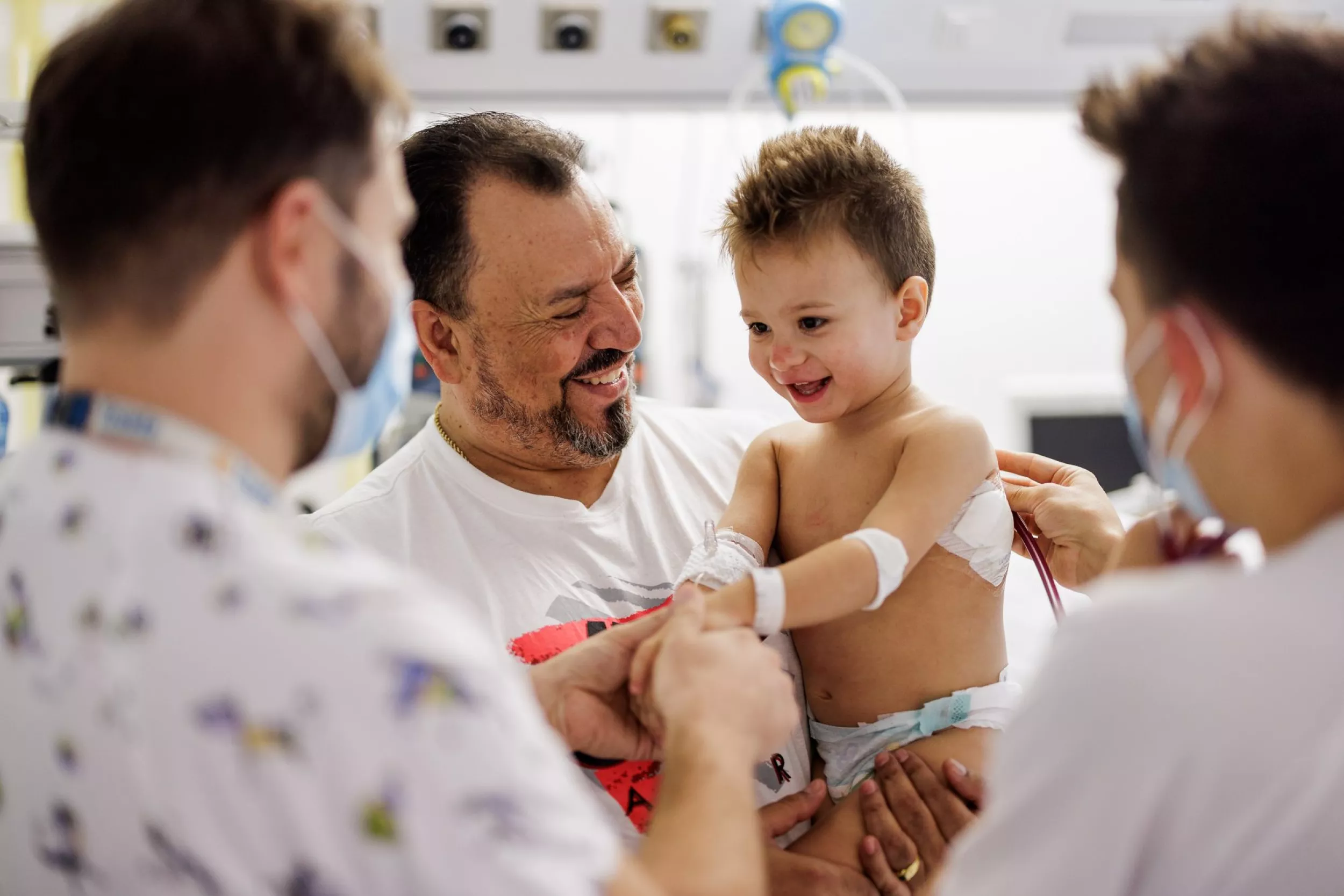 Un papa amb el seu fill contents i dos infermers observant com ausculten el nen