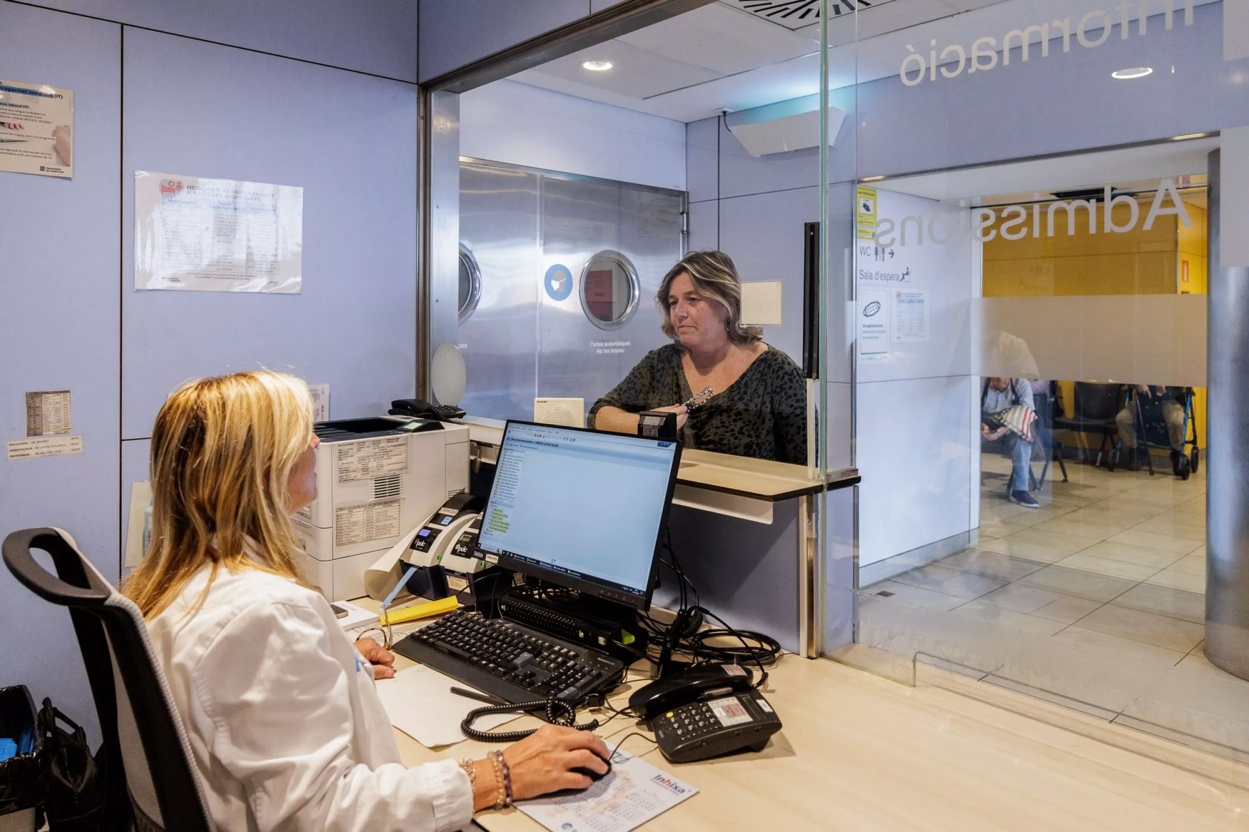 Pacient lliurant a l'administrativa dades per a l'ingrés