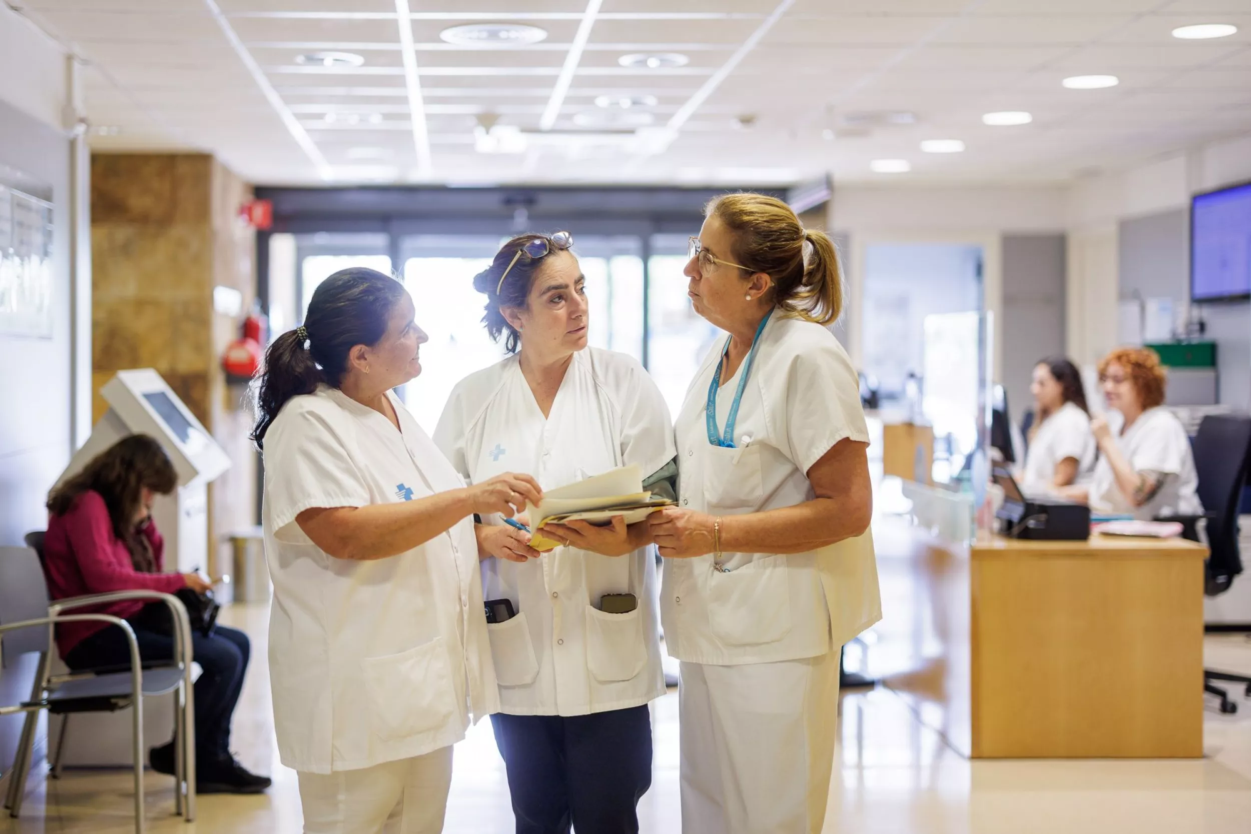 Tres trabajadoras del CAP hablando entre ellas en la sala de espera del centro
