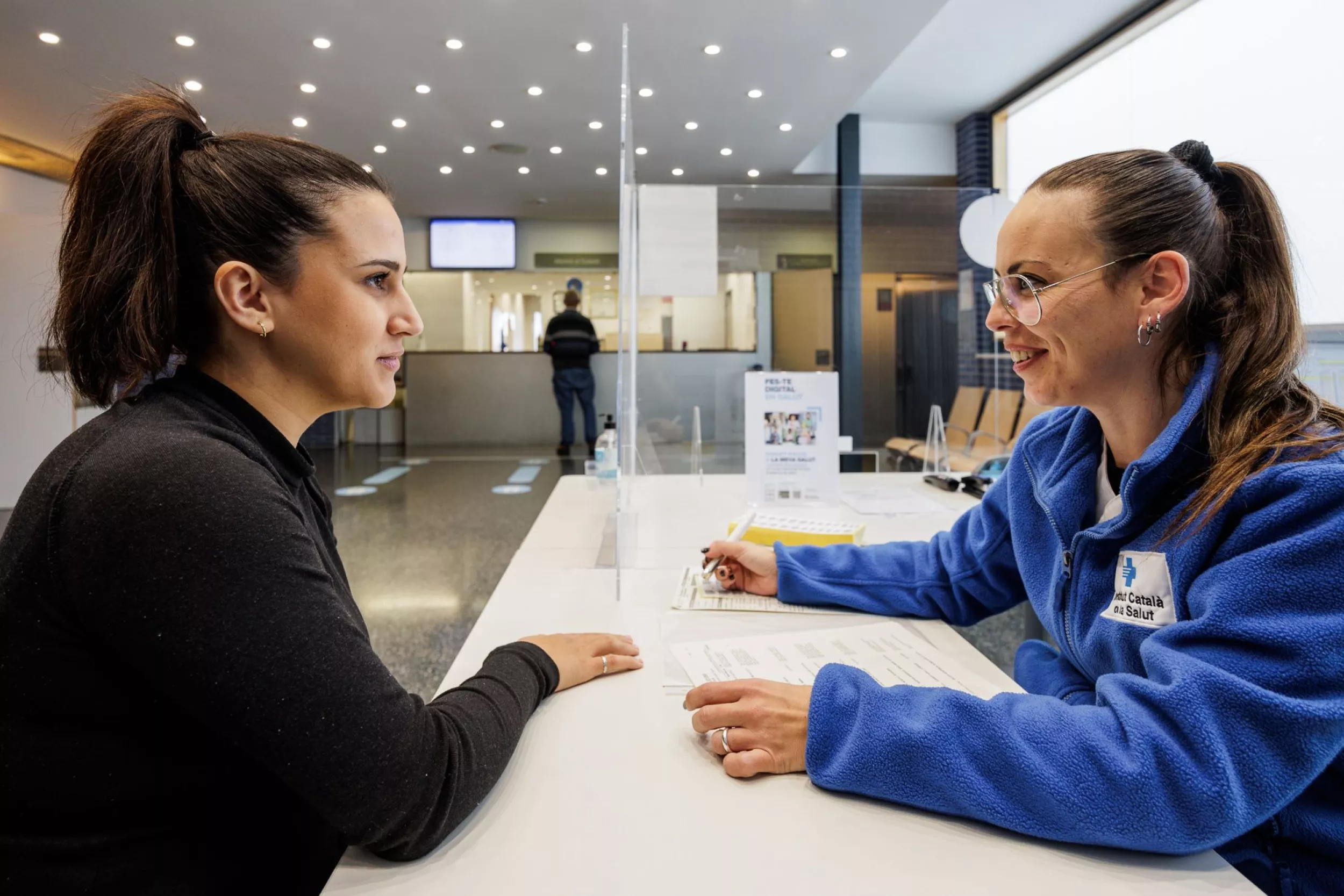 Administrativa atenent una pacient per fer tràmits i gestions