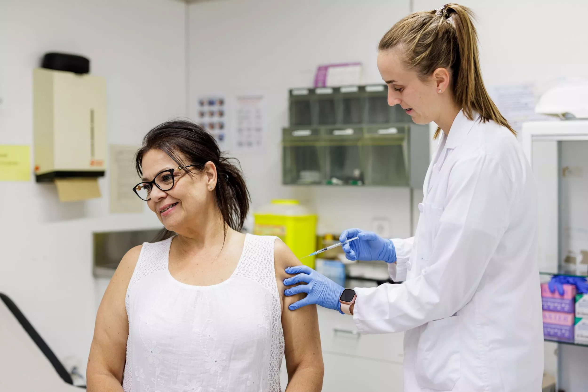 Enfermera administrando una vacuna a una paciente sonriente