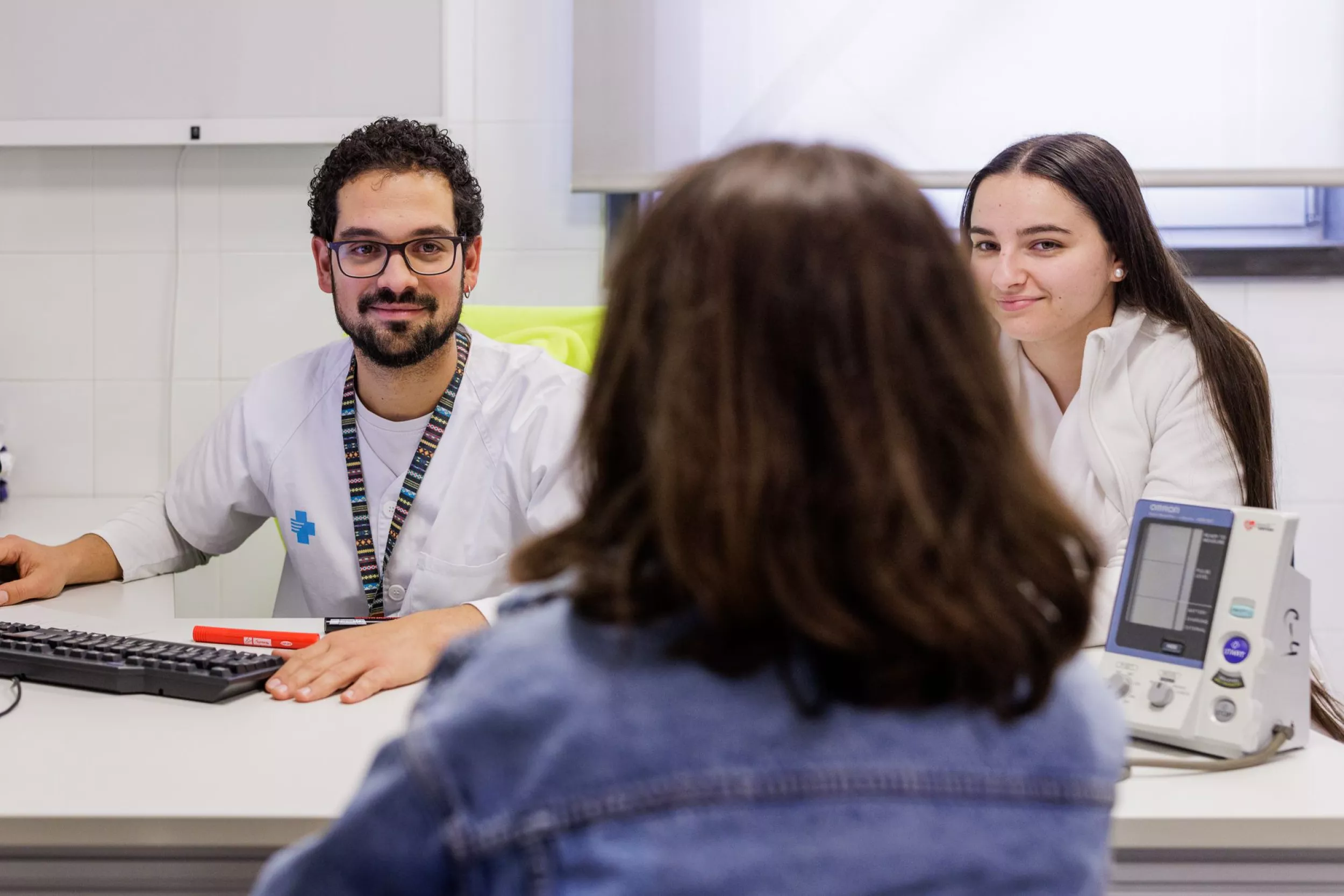 Metge i resident parlant amb una pacient en una consulta