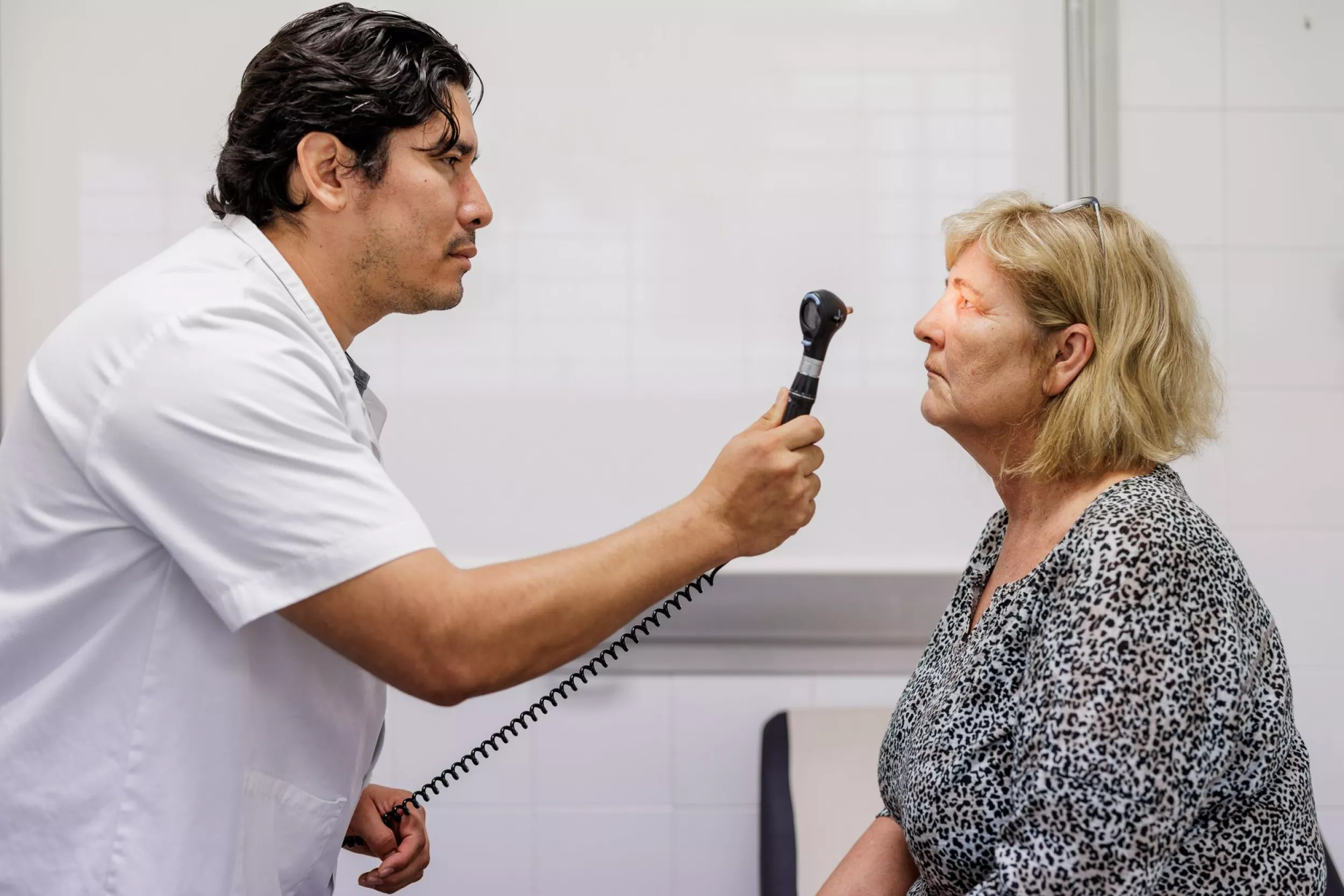 Professional sanitari examinant els ulls d'una pacient amb un oftalmoscopi