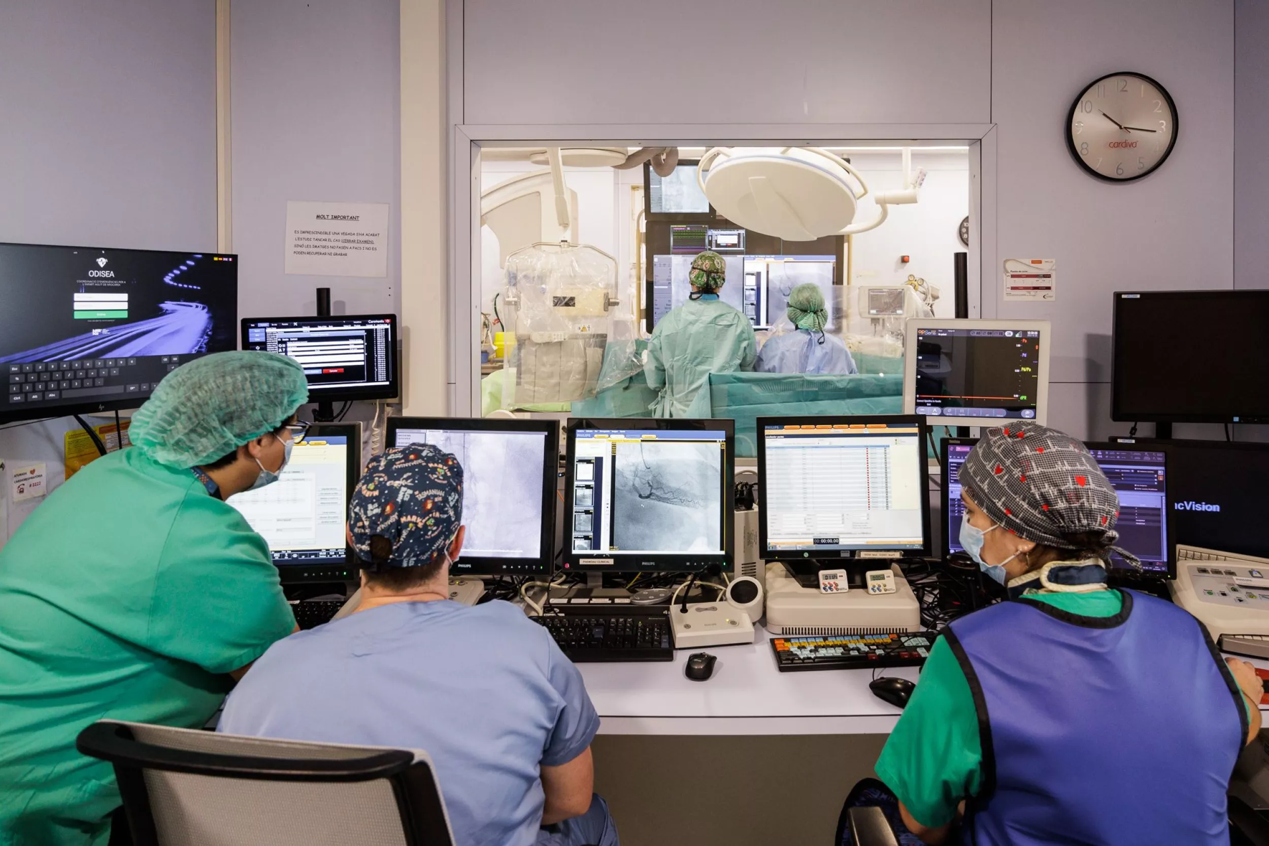  Metges de cardiologia debatent al voltant de diverses pantalles amb informació de pacients