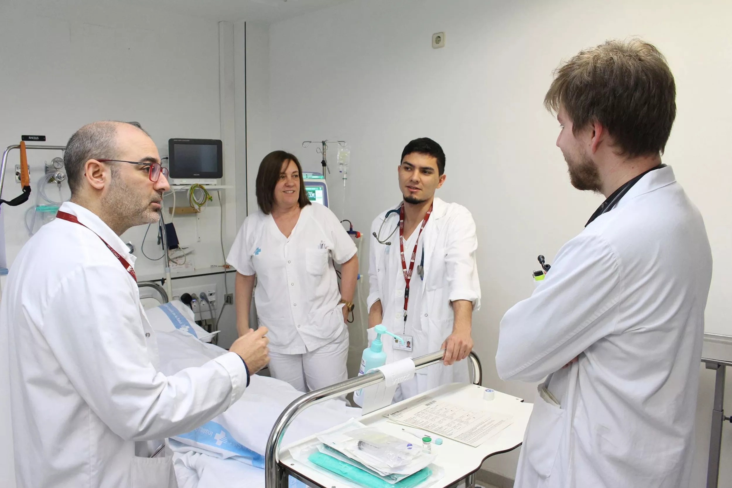Grup de quatre metges parlant entre ells al voltant d'un llit dins una habitació de l'hospital