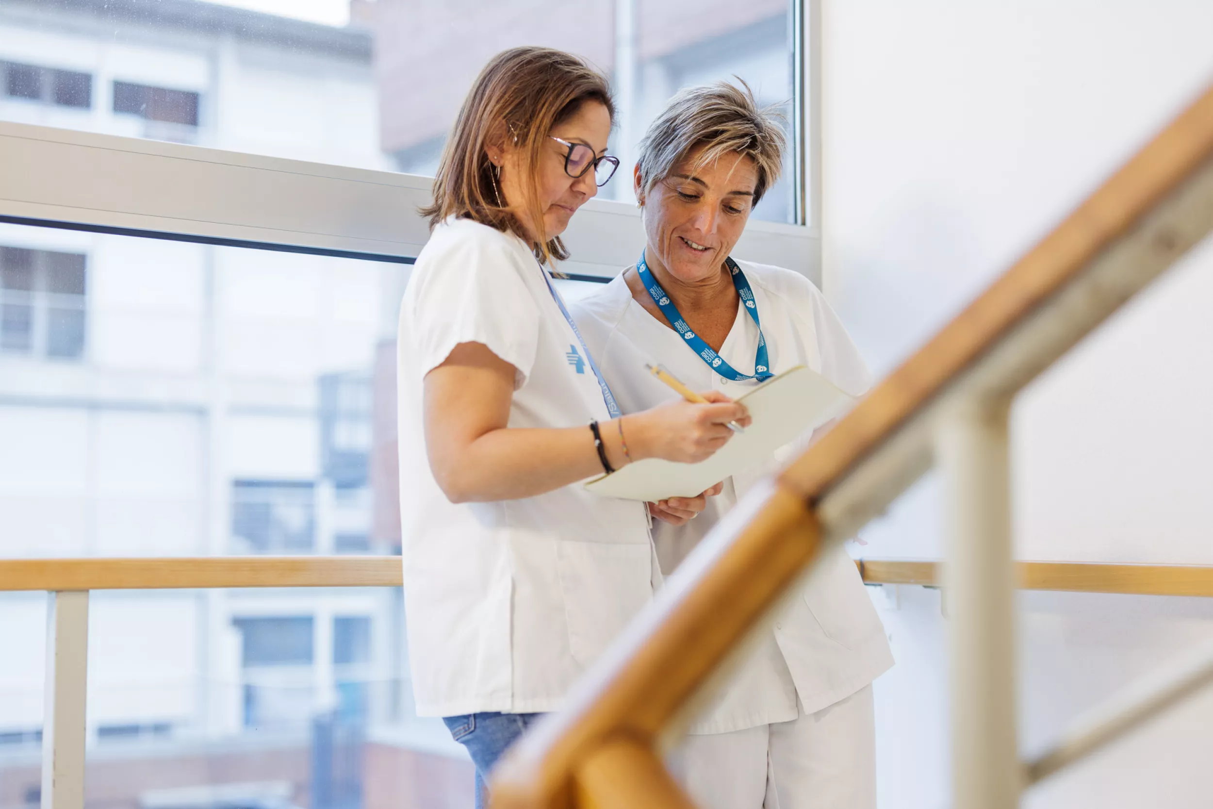Dues infermeres penjant escales i mirant informe mèdic