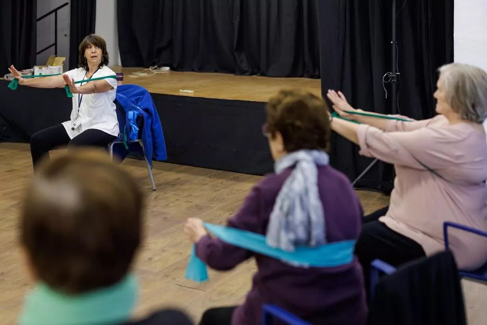 Personas mayores en una sala haciendo ejercicio con una enfermera
