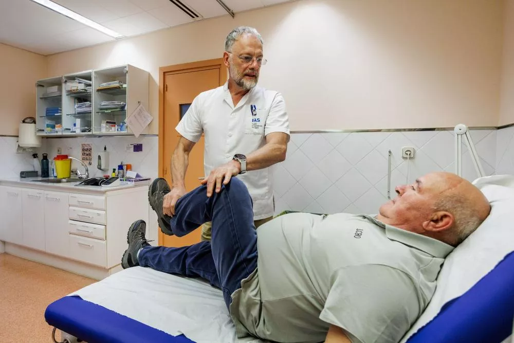 Médico flexionando la rodilla de un paciente de avanzada edad