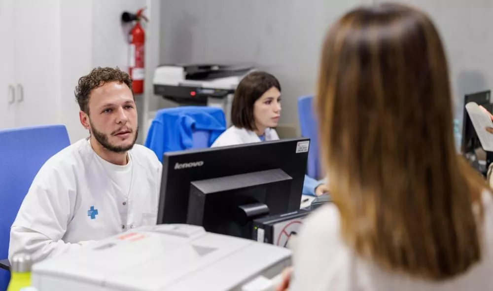 Dos administrativos del CAP atendiendo a una paciente