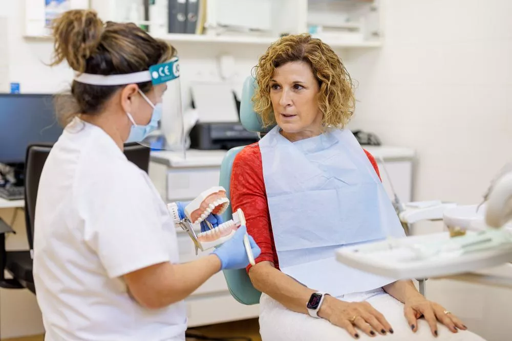 Médico de odontología mostrándole a una paciente como cepillarse los dientes