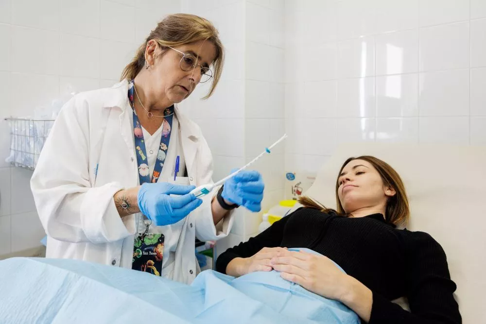 Médico enseñando un utensilio a una paciente tumbada en una camilla