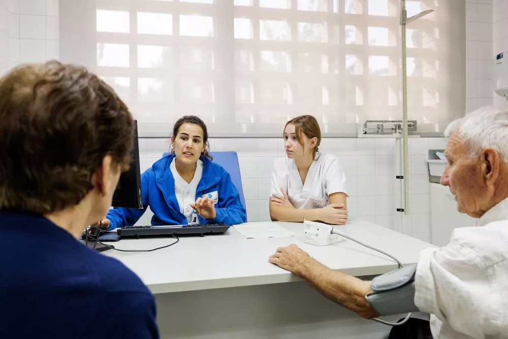 Enfermeras hablando con dos pacientes mientras toman la tensión a uno de ellos
