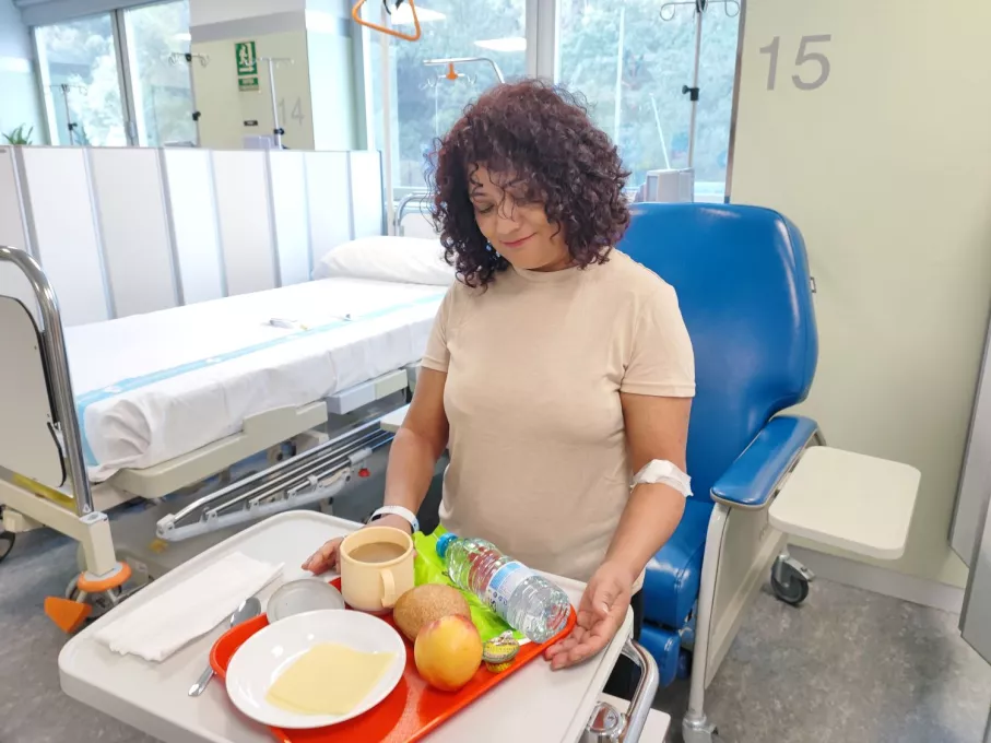 Una usuària de l'Hospital de Dia rep la safata amb l'esmorzar, ara amb una selecció de productes més saludables.