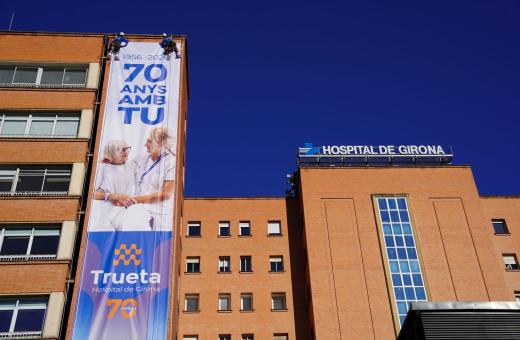 Operaris instal·len a la façana de l'Hospital Trueta la lona commemorativa del 70è aniversari del centre