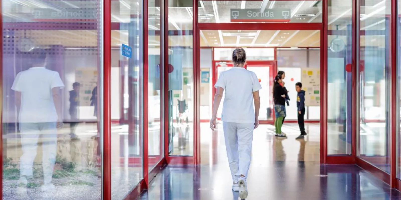 Persona amb uniforme blanc caminant pel passadís de l'hospital