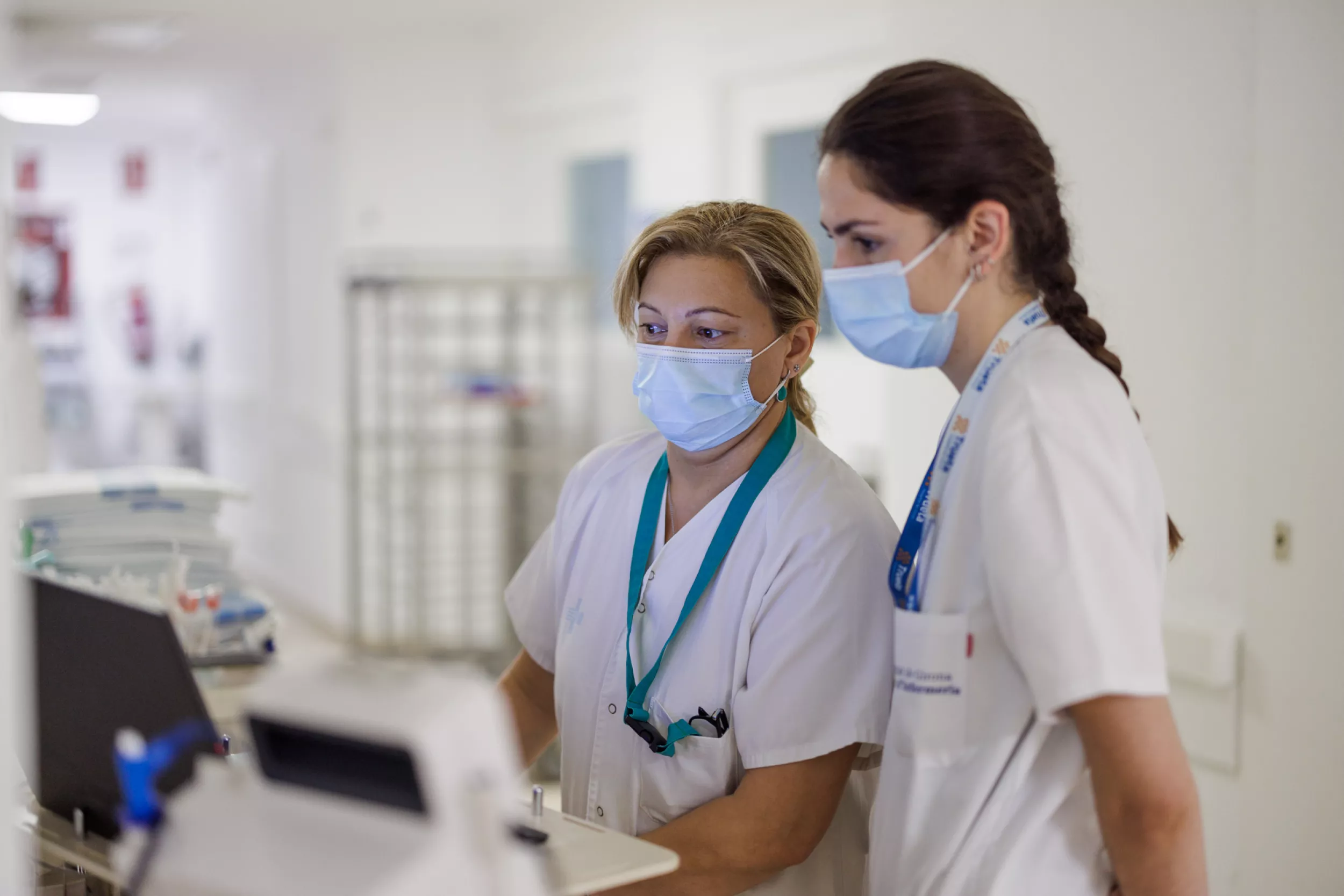 Una infermera mostrant alguna cosa al monitor a una estudiant d'infermeria.