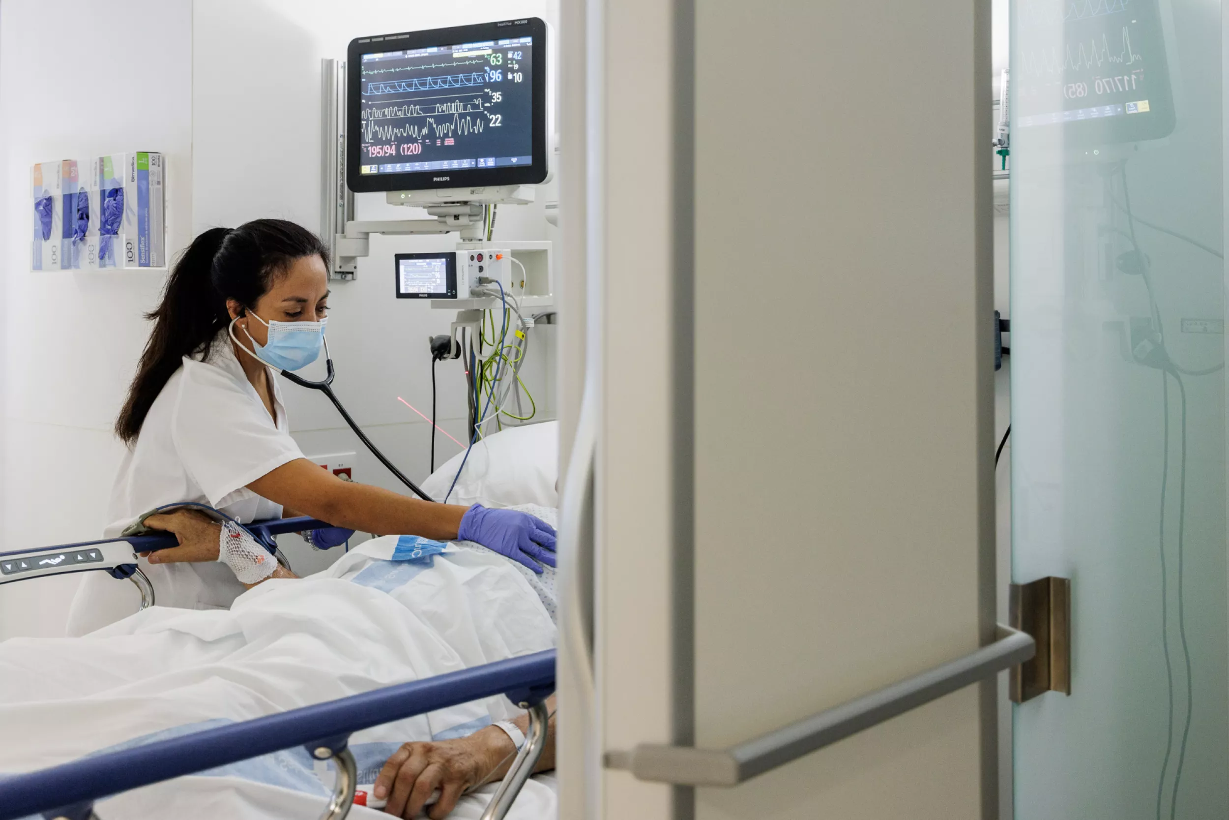 Una doctora auscultant un pacient.