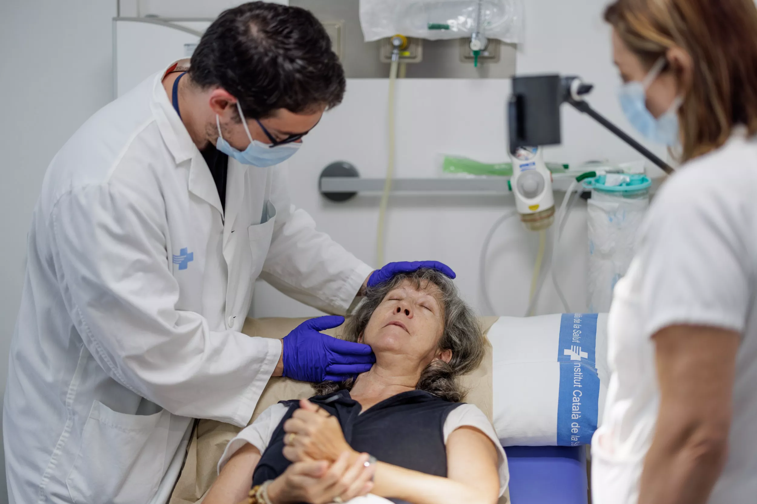 Un metge assistint a una pacient davant una infermera.