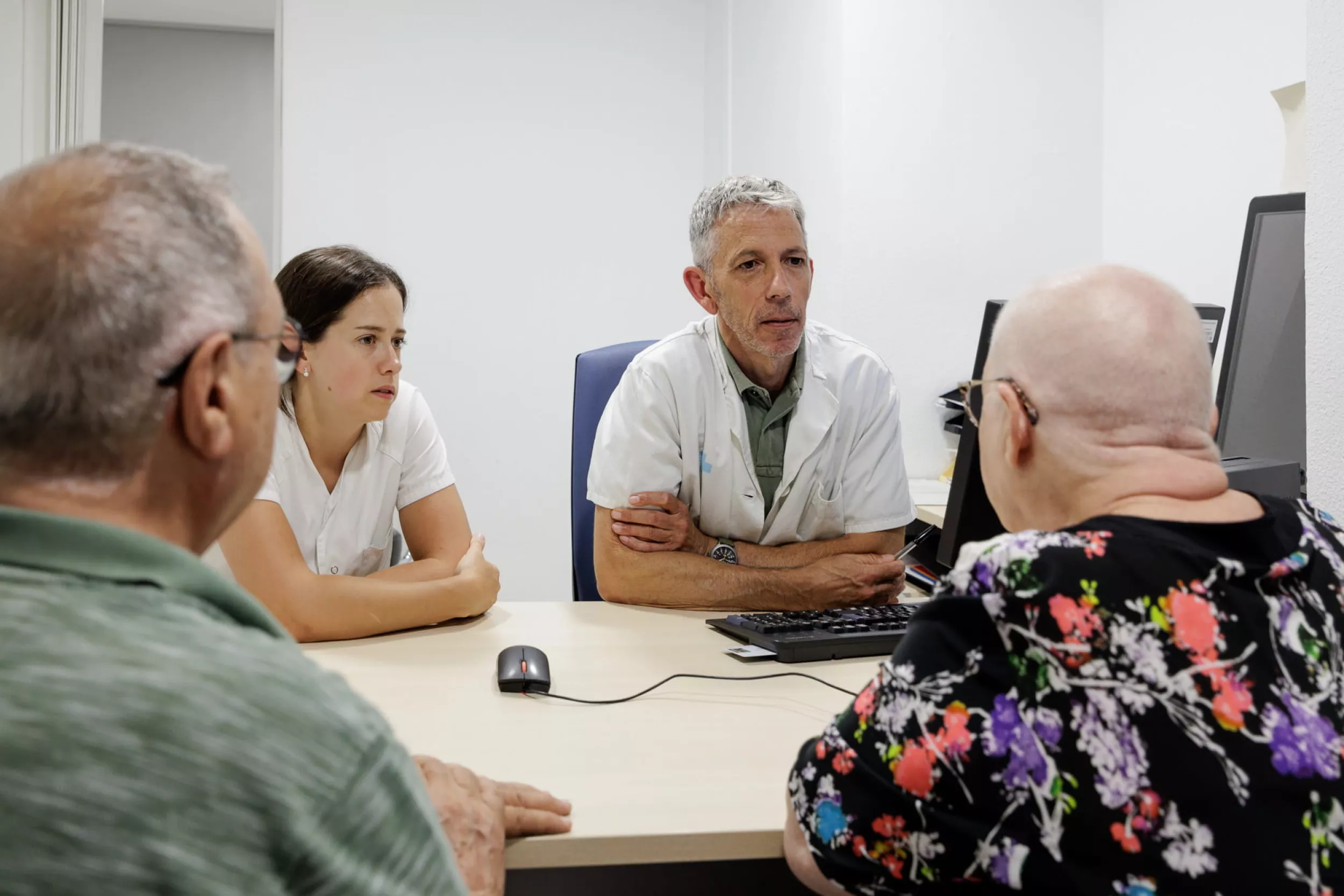 Metge i infermera parlant amb un pacient i el seu acompanyant