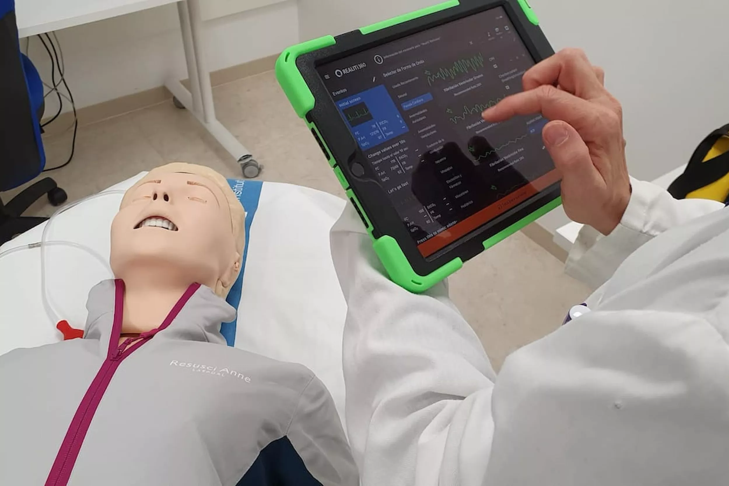 Persona amb bata blanca utilitzant una tauleta per monitoritzar un maniquí de simulació mèdica