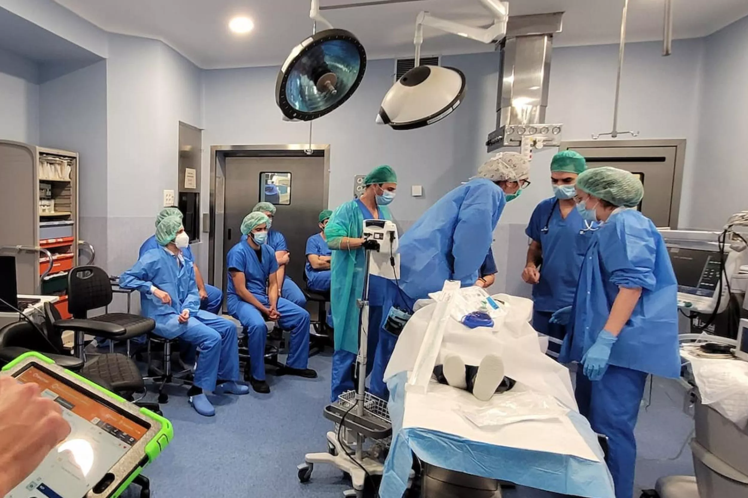Grup de professionals sanitaris amb equips de protecció en un quiròfan, realitzant una formació amb residents