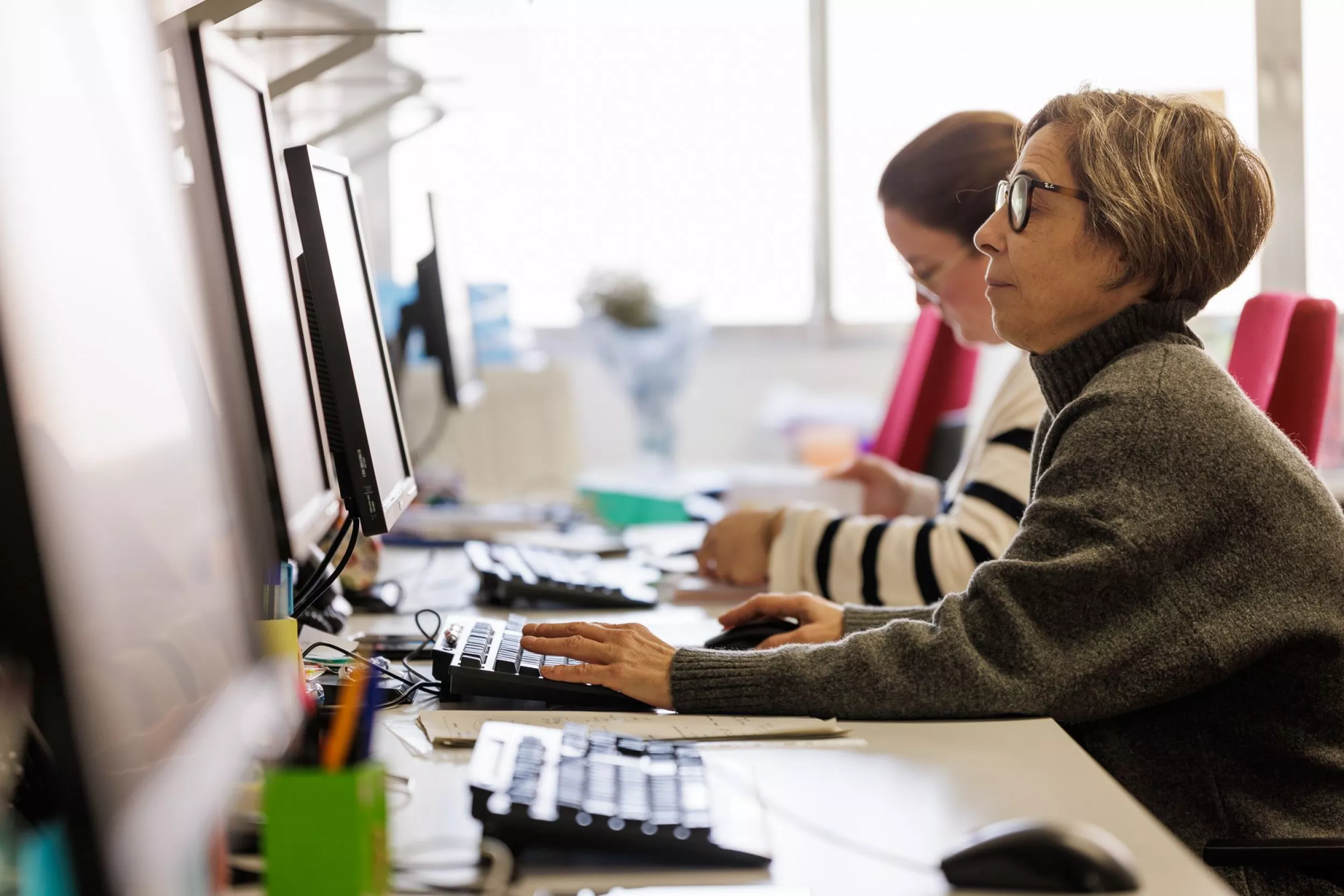 Profesionales de atención paliativa trabajando con ordenadores en un espacio de trabajo compartido