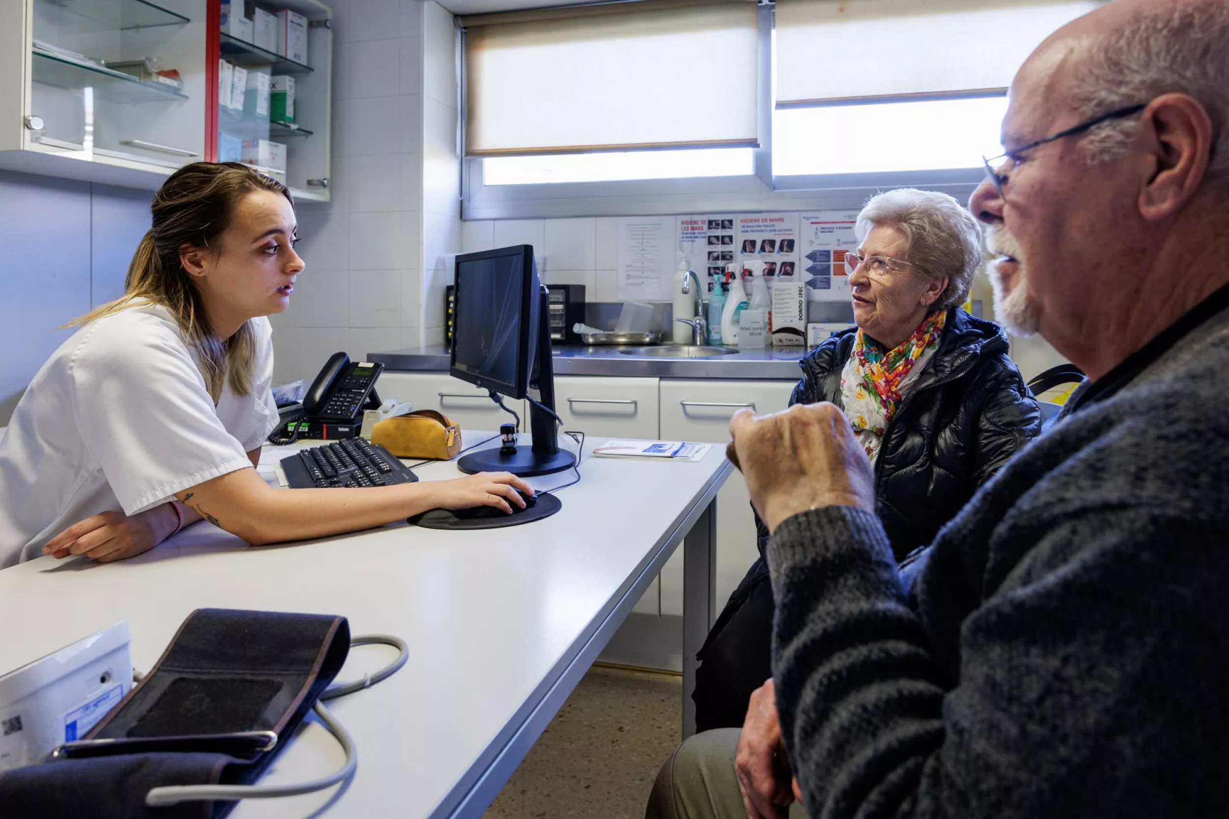 Professional de la salut atén una parella de persones grans en una consulta mèdica