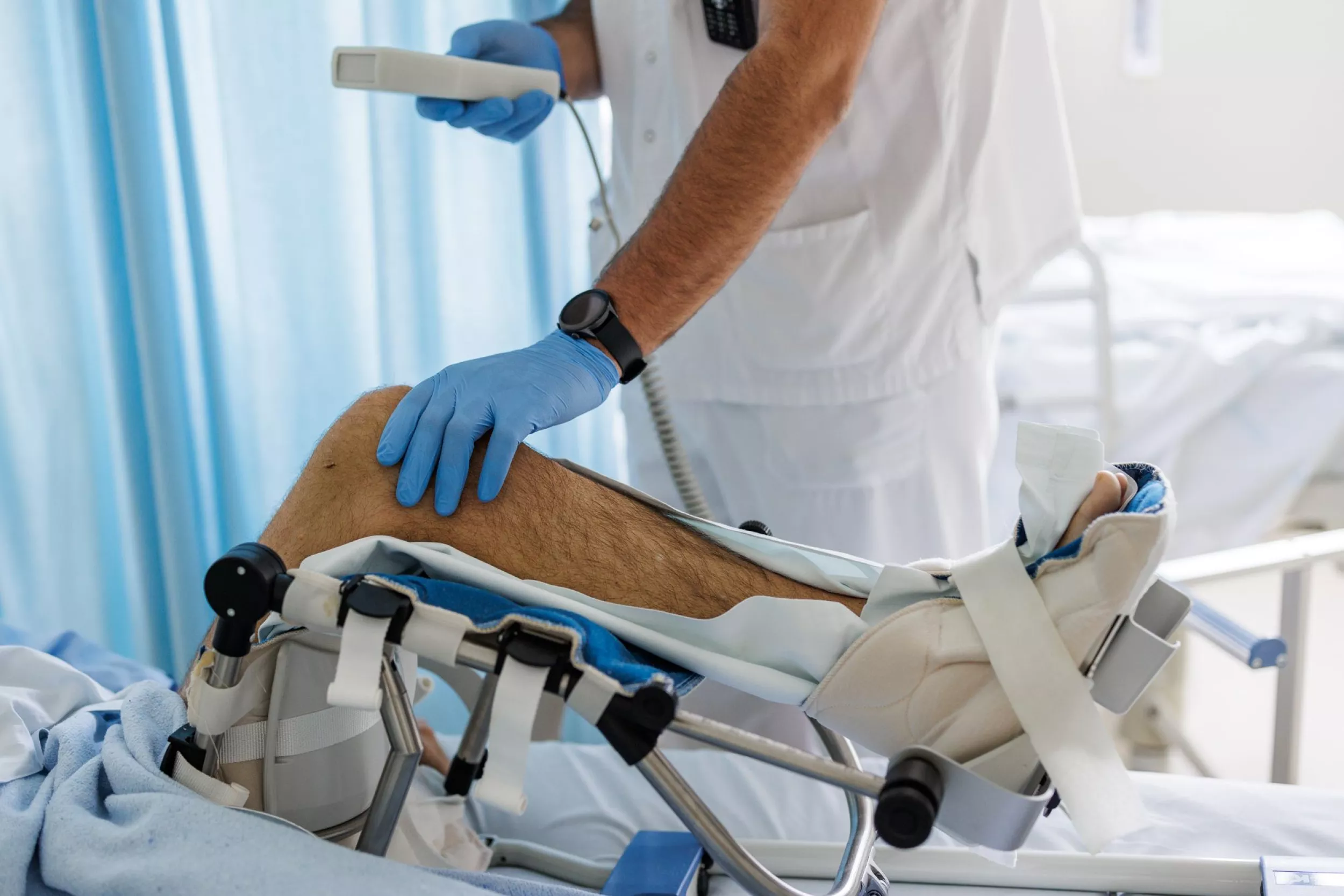  Metge fent proves a la cama a un pacient. Només es mostren els braços del metge i la cama del pacient