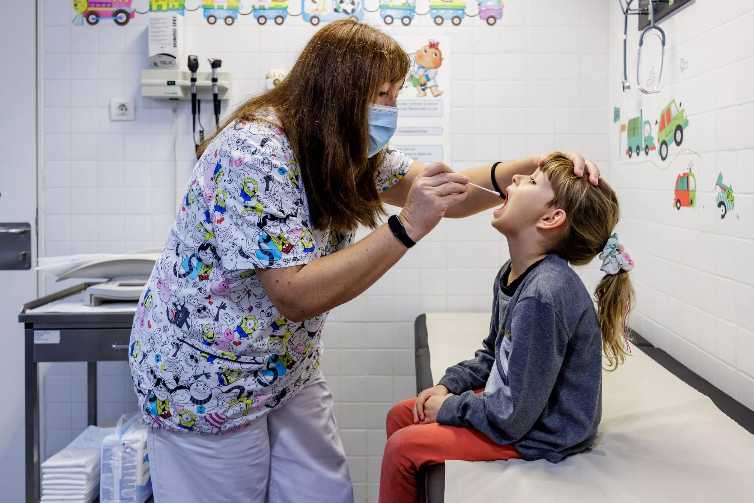 Enfermera revisando la garganta de una niña en una consulta pediátrica