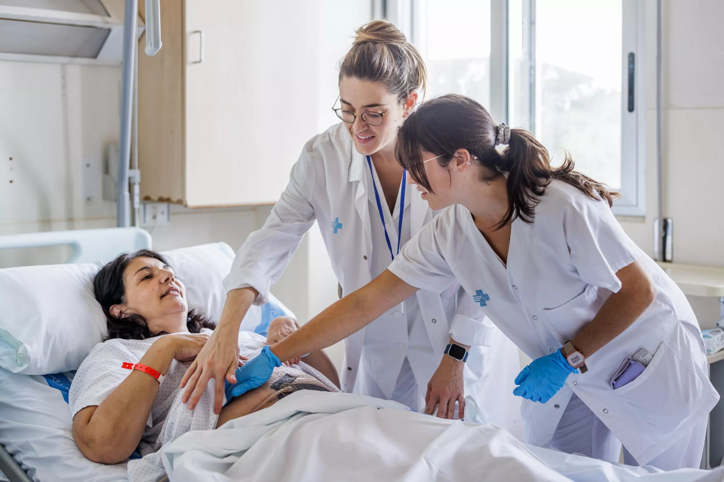 Dos enfermeras controlando si una paciente tiene dolor en el abdomen