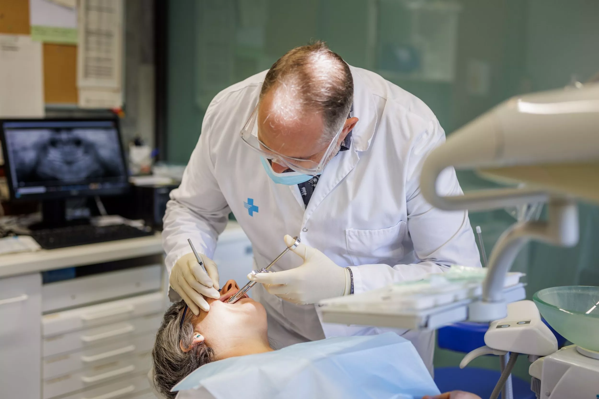 Dentista atenent una pacient amb una radiografia a la pantalla