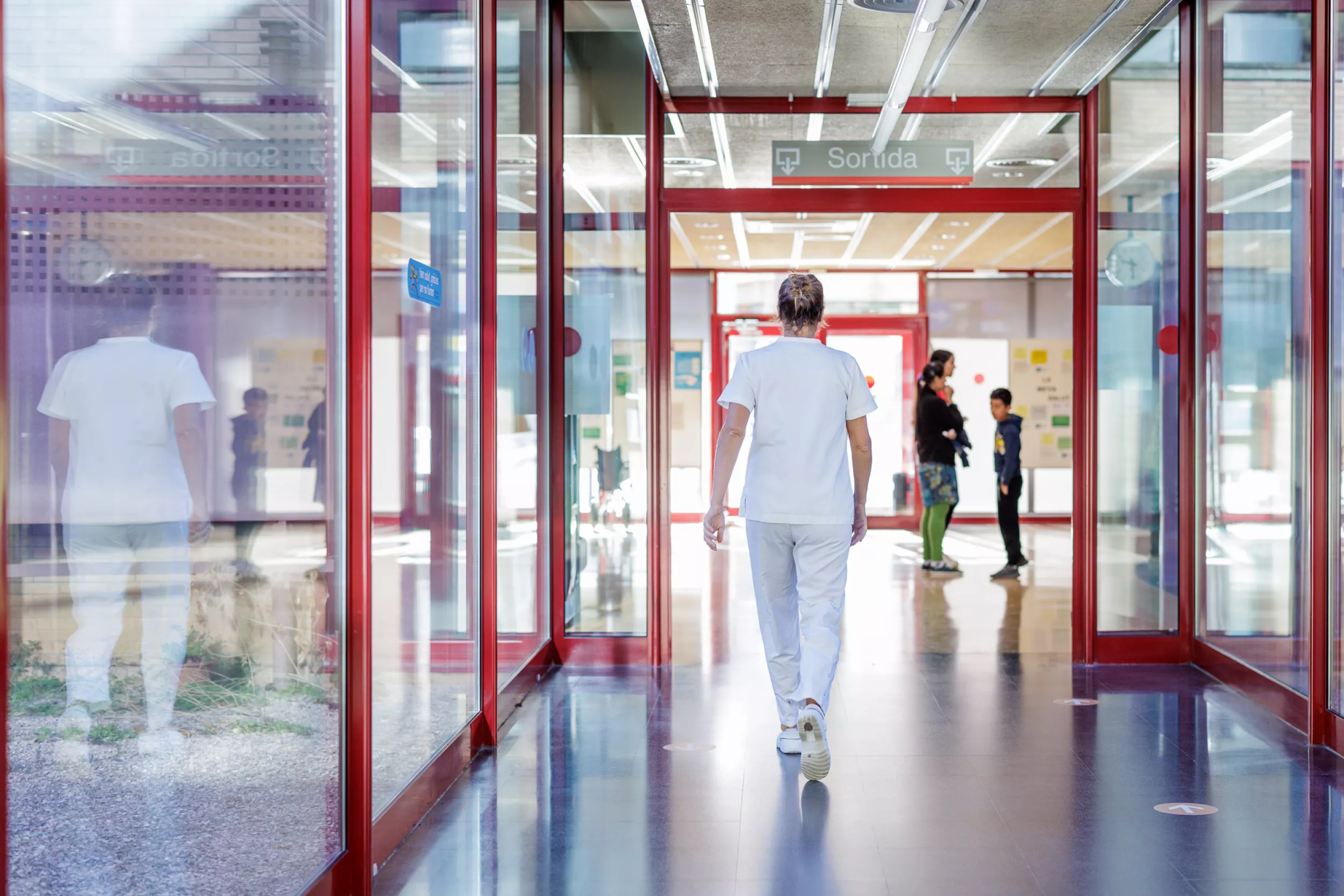 Persona amb uniforme blanc caminant pel passadís de l'hospital