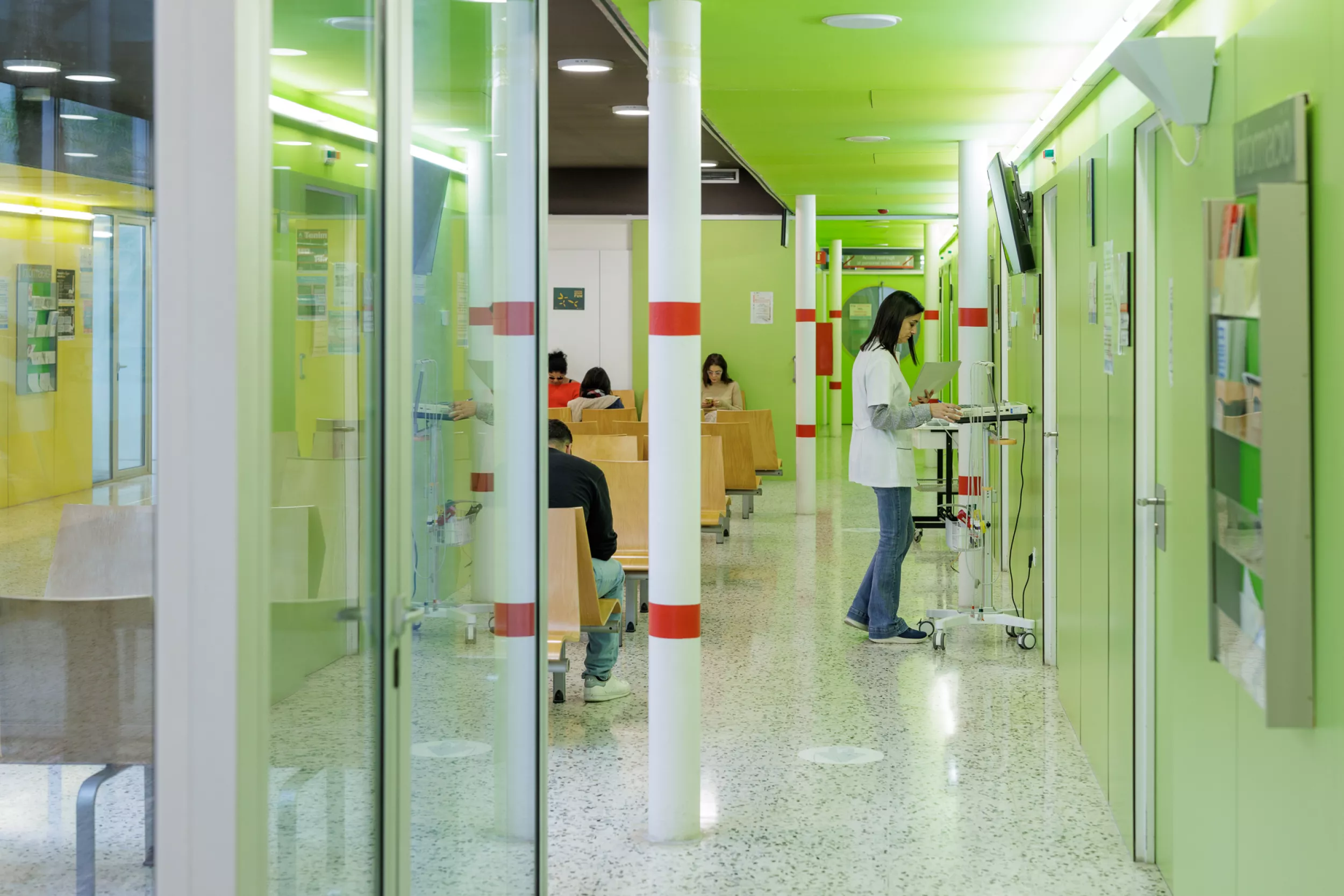 Sala d’espera de l’hospital amb infermera de peu que mira històries clíniques.