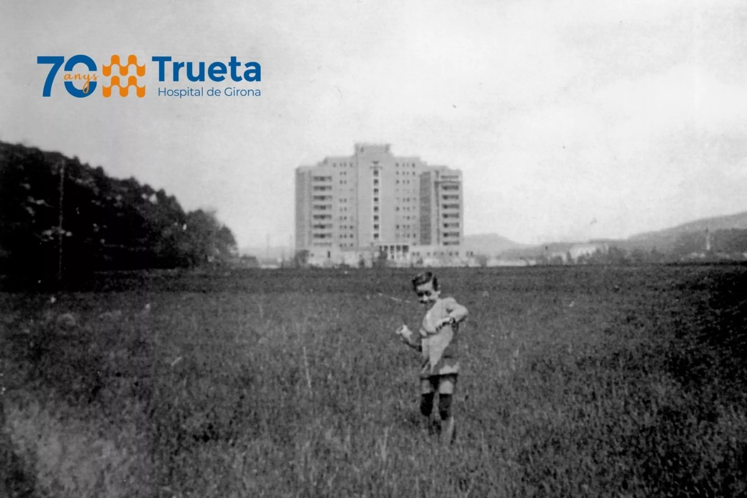 Imatge històrica de l'edifici del Trueta amb un infant jugant a les afores, encara sense urbanitzar