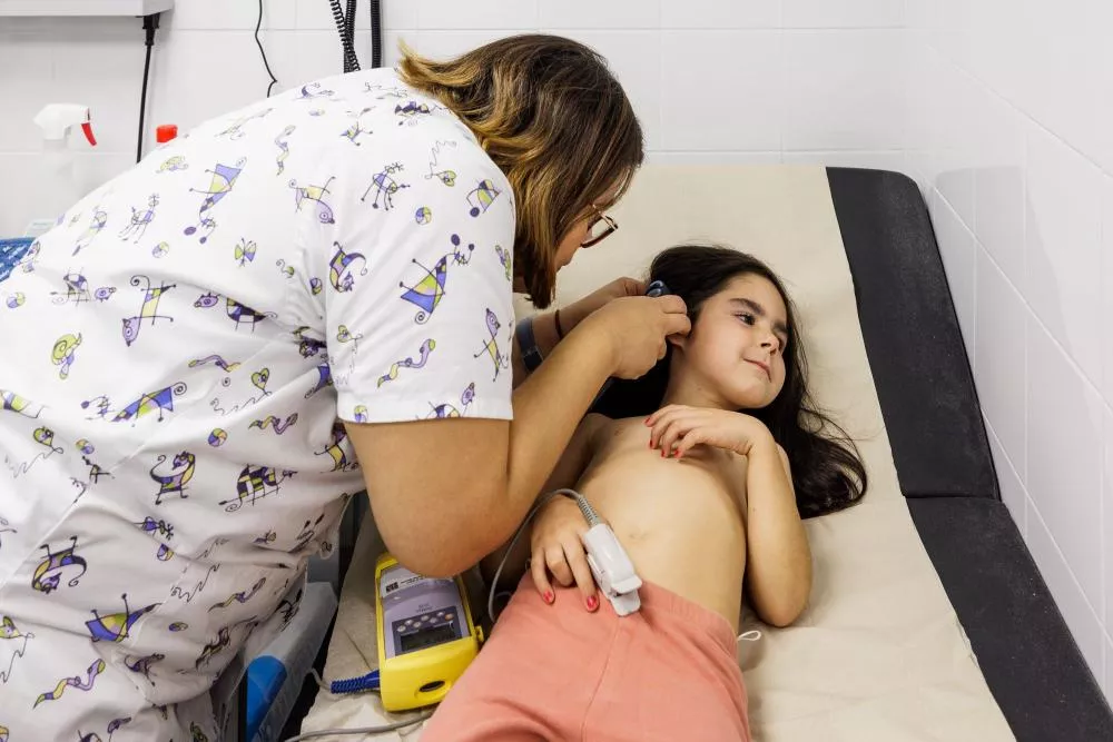 Médico inspeccionando el oído de una niña