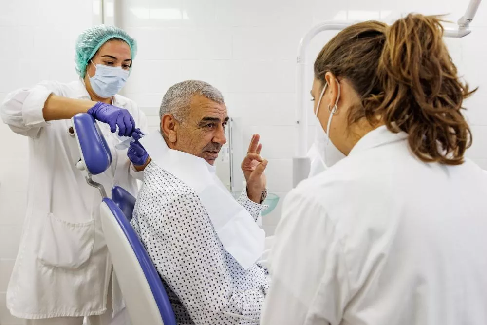Médicos hablando con un paciente que está sobre un sillón
