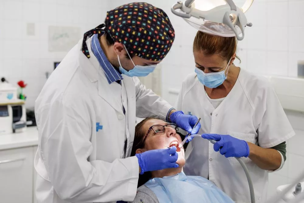 Dos médicos tratando odontológicamente a una paciente