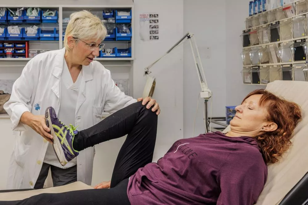 Médico flexionando la pierna de una paciente